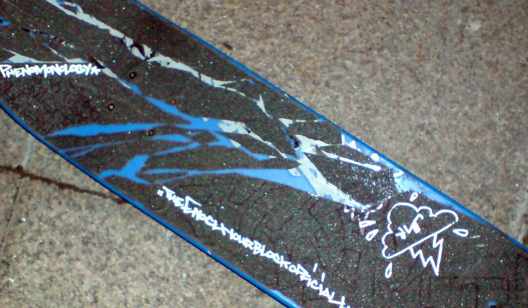 A black skateboard with blue and white paint streaks and writing